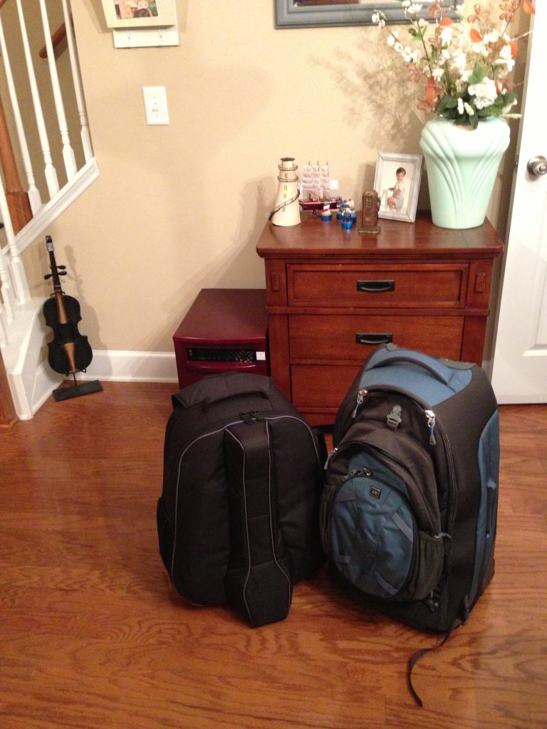 Two packed suitcases near a wooden dresser and stairs.