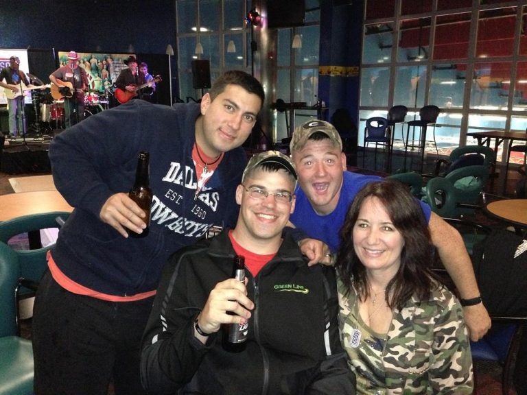 Four friends smiling together at a social gathering indoors.